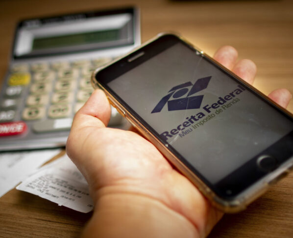 Imagem colorida de um celular com o símbolo da Receita Federal Imposto de Renda consulta - Metrópoles
