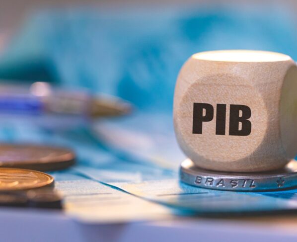 Imagem de um dado com a inscrição "PIB" sobre uma moeda de real - Metrópoles